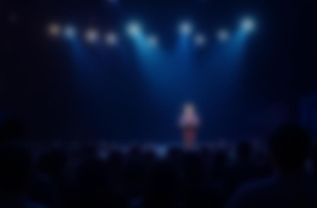 Pessoa falando confiante em um palco com luzes